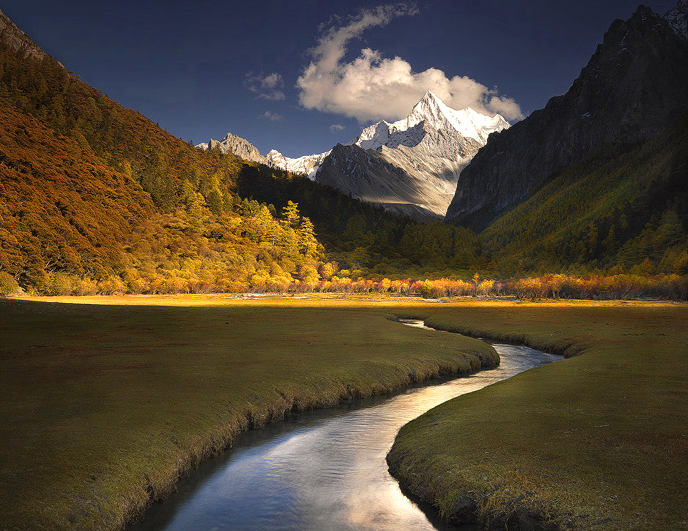 Symmetry A tranquil stream meanders through the park like meadows of Yading Nature Reserve, one of the most spectacular and least...